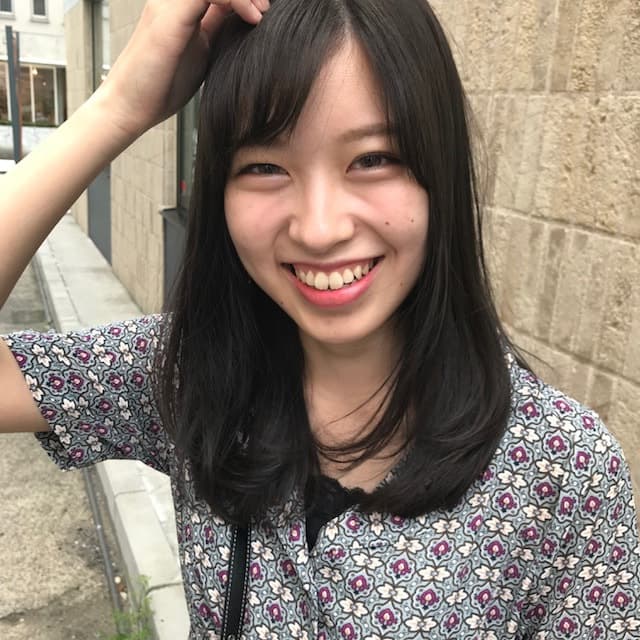 頭に手を置くセミロングの女性