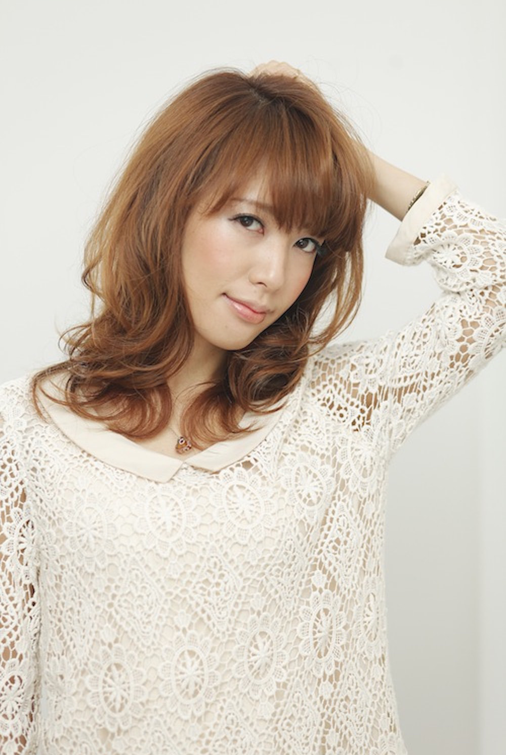 頭に手をかけてる愛されミディアムヘアの女性